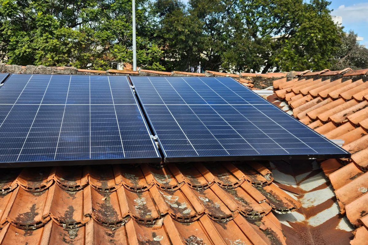 Módulos solares vistos de perto, no encontro de duas águas de um telhado de
                  telha cerâmica